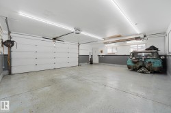 Spacious garage featuring a sectional overhead door, concrete flooring, linear ceiling lighting, and built-in shelving - 