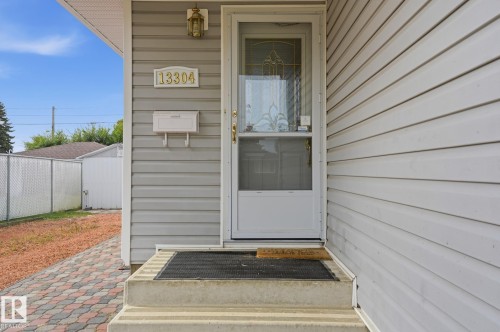Vinyl siding exterior featuring a decorative address plaque, wall-mounted mailbox, and an exterior light fixture - 13304 63 Street Nw, Edmonton, AB 