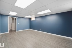Spacious room with blue-painted walls, wood-finish flooring, and a drop ceiling with integrated lighting - 