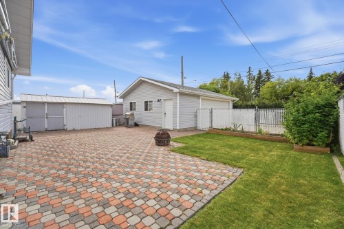 Paver patio, detached garage, manicured lawn, white vinyl fencing, and a storage shed - 13304 63 Street Nw, Edmonton, AB 