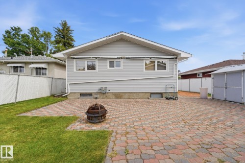 Paved patio area, grey siding exterior, chain-link fence, and a storage shed - 13304 63 Street Nw, Edmonton, AB 