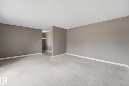 Neutral tone wall paint, light-toned carpeting, white trim, and a textured ceiling - 13304 63 Street Nw, Edmonton, AB 