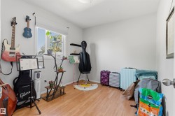 Light-toned wood-finish flooring, white painted walls, and a single window with blinds - 
