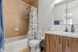 Full bathroom featuring a tub-shower combination with tiled surround, a toilet, a wood-finish vanity with an integrated sink, and a mirrored medicine cabinet - 