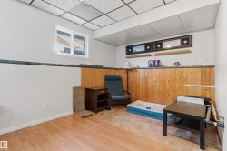 Wood-finish flooring with partial tile inlay, paneled wood wainscoting, and a drop ceiling with integrated lighting - 