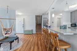 Open concept living area featuring wood-finish flooring, a kitchen island with stone countertop, and pendant lighting - 