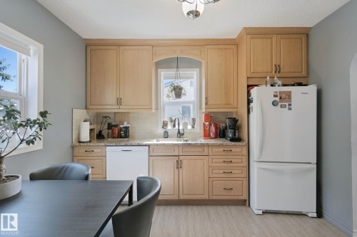 Kitchen featuring natural wood cabinetry, stone countertops, a tile backsplash, and wood-finish flooring - 12035 83 Street Nw, Edmonton, AB 
