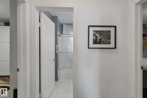 Hallway featuring white panel doors, white trim, and a white wall finish - 12035 83 Street Nw, Edmonton, AB 