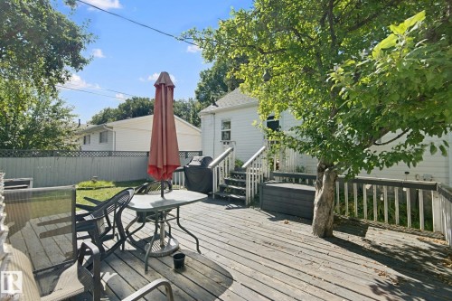 Expansive wood deck with a built-in storage bench and mature shade tree - 12035 83 Street Nw, Edmonton, AB 