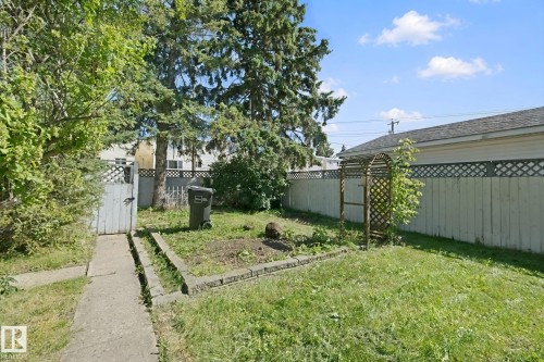 Backyard features a concrete pathway, a wooden gate, and a wooden lattice fence - 12035 83 Street Nw, Edmonton, AB 