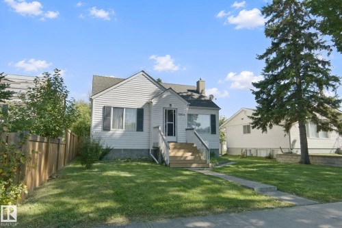 Siding exterior with a gabled roof, complemented by a front yard featuring a concrete walkway and mature landscaping - 12035 83 Street Nw, Edmonton, AB 