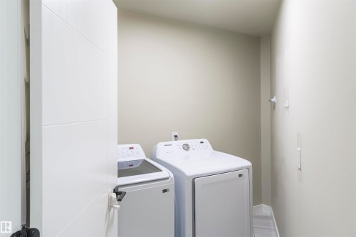 Dedicated laundry area featuring modern appliances, neutral wall tones, and wood-finish flooring - 5010 147 Street Nw, Edmonton, AB 