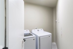 Dedicated laundry area featuring modern appliances, neutral wall tones, and wood-finish flooring - 