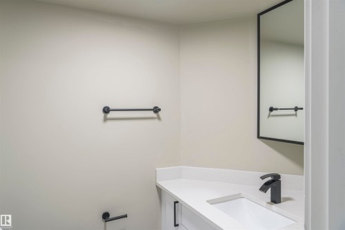 Contemporary vanity with a white countertop and integrated sink, complemented by a matte black faucet - 5010 147 Street Nw, Edmonton, AB 