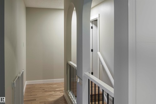 Hallway featuring light-toned wood-finish flooring, white baseboards, and neutral wall paint - 5010 147 Street Nw, Edmonton, AB 