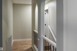 Hallway featuring light-toned wood-finish flooring, white baseboards, and neutral wall paint - 