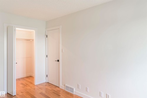 Room featuring light wood-finish flooring, white painted walls, and a closet with bifold doors - 5010 147 Street Nw, Edmonton, AB 