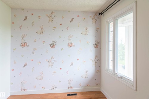 Room featuring light-toned wood-finish flooring, white baseboards, and a large window with white trim - 5010 147 Street Nw, Edmonton, AB 