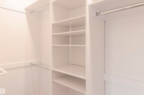 Custom closet system featuring white shelving units, multiple hanging rods, and integrated adjustable shelving - 5010 147 Street Nw, Edmonton, AB 
