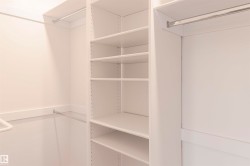 Custom closet system featuring white shelving units, multiple hanging rods, and integrated adjustable shelving - 