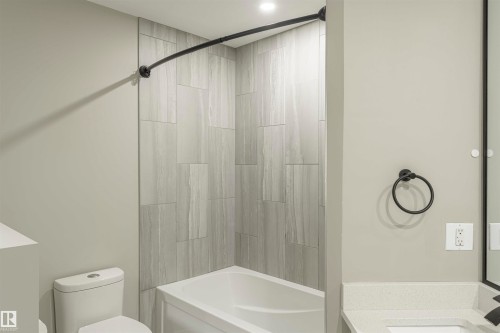 Bathtub and shower combination featuring large format grey tile surround and a curved matte black shower rod - 5010 147 Street Nw, Edmonton, AB 