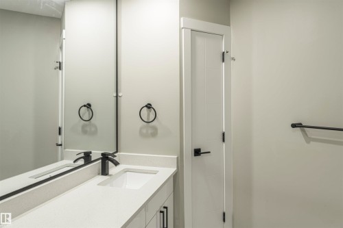 Contemporary bathroom vanity featuring a rectangular undermount sink, light-toned countertop, and matte black faucet - 5010 147 Street Nw, Edmonton, AB 