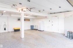 Spacious garage featuring a durable epoxy speckled floor, white paneled ceiling, and ample wall shelving - 
