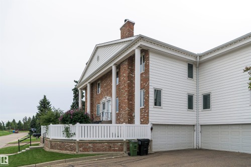 Brick and white siding exterior featuring a columned portico, gable roofline, and attached two-car garage - 5010 147 Street Nw, Edmonton, AB 