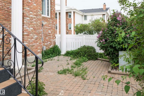 Brick exterior featuring white architectural columns, black wrought iron railings, and a paver stone patio - 5010 147 Street Nw, Edmonton, AB 