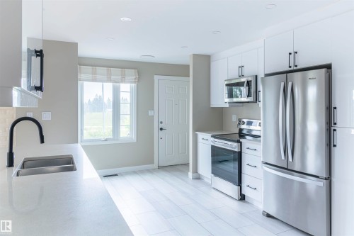 Modern kitchen featuring a stainless steel French door refrigerator, matching stainless steel range, and an over-range microwave - 5010 147 Street Nw, Edmonton, AB 