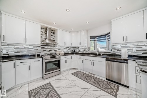White cabinetry with sleek hardware, stainless steel appliances, dark countertops, a tiled backsplash, and recessed lighting - 4608 43 Avenue Nw, Edmonton, AB 