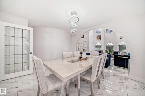 White marble-look tile flooring, arched doorway, and a modern tiered chandelier - 4608 43 Avenue Nw, Edmonton, AB 