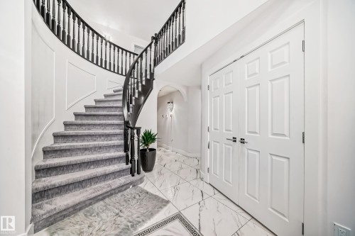 Curved staircase with carpeted treads and dark wood banister - 4608 43 Avenue Nw, Edmonton, AB 