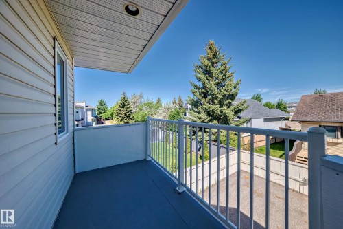 Balcony with white railing and composite decking, featuring a white vinyl-sided exterior wall - 4608 43 Avenue Nw, Edmonton, AB 