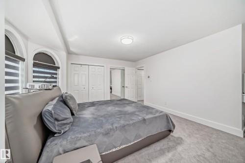 Arched windows with layered shades, double bi-fold closet doors, recessed ceiling lighting, and carpeted flooring - 4608 43 Avenue Nw, Edmonton, AB 
