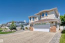 Two-story residence featuring light-colored siding, a prominent two-car garage with decorative windows, and an exposed aggregate driveway - 4608 43 Avenue Nw, Edmonton, AB 