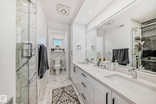 Dual vanity with undermount sinks, stone countertops, and integrated mirror - 4608 43 Avenue Nw, Edmonton, AB 