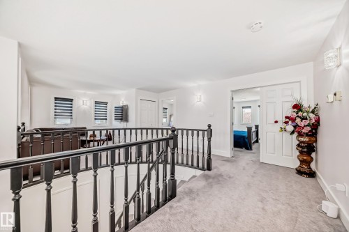 Loft area with dark wood balusters, light gray carpeting, and multiple windows with horizontal blinds - 4608 43 Avenue Nw, Edmonton, AB 