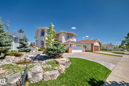 Exterior featuring arched windows, an attached garage, a paved driveway, and a rock garden with water feature - 4608 43 Avenue Nw, Edmonton, AB 