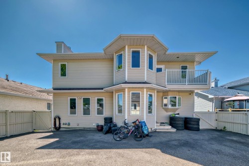 Rear exterior with light-colored siding, multiple large windows, and an upper-level balcony with white railings - 4608 43 Avenue Nw, Edmonton, AB 