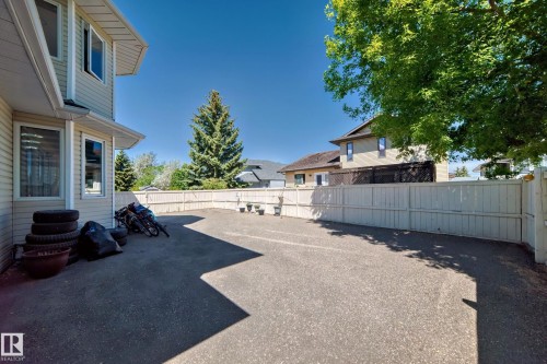 Paved outdoor space featuring a perimeter fence and mature trees - 4608 43 Avenue Nw, Edmonton, AB 
