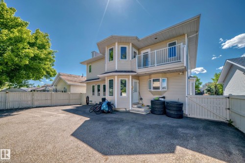 Siding exterior with multiple windows, a second-story balcony with white railings, and a fenced perimeter - 4608 43 Avenue Nw, Edmonton, AB 
