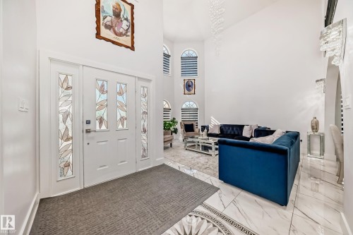 Vaulted ceilings, arched windows with horizontal blinds, decorative tile flooring, and a white entry door with frosted glass panels - 4608 43 Avenue Nw, Edmonton, AB 