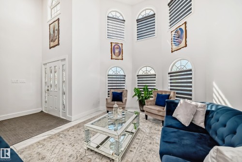 Double-height living space featuring multiple arched windows with privacy blinds, a white double entry door with decorative glass inserts, and light-toned tile flooring - 4608 43 Avenue Nw, Edmonton, AB 