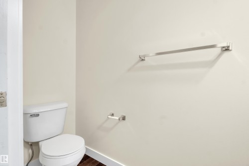 White toilet with a dual flush mechanism, wood-finish flooring, and light-toned wall paint - 3071 Carpenter Landing Sw, Edmonton, AB 