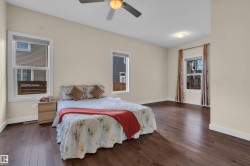 Spacious room featuring rich wood-finish flooring, light-colored walls, and multiple windows with white trim - 