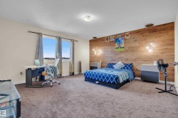 Spacious room featuring a prominent wood-panel accent wall with integrated pendant lighting - 