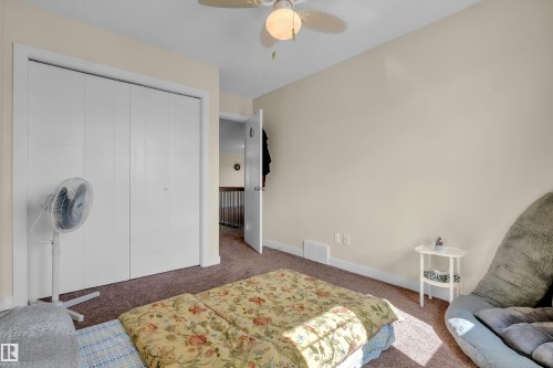 Spacious bedroom featuring neutral wall tones, textured carpeting, a ceiling fan with integrated lighting, and a bi-fold closet with white panel doors - 3071 Carpenter Landing Sw, Edmonton, AB 