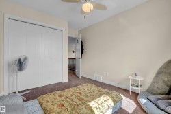 Spacious bedroom featuring neutral wall tones, textured carpeting, a ceiling fan with integrated lighting, and a bi-fold closet with white panel doors - 