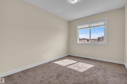 Room featuring a multi-pane window with white trim, neutral-toned walls, and brown carpeting - 3071 Carpenter Landing Sw, Edmonton, AB 